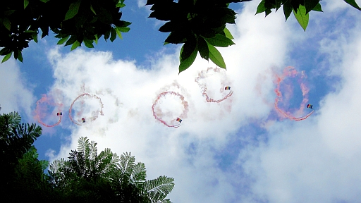 Five members of the 8.1 Parachute Brigade jumped out of the helicopter at about 1300 m high and ignited colourful smoke bomb as they sprialled down.  A pattern of five colored rings was created to resemble a rainbow.  Photo taken by Queenie Lam of the Observatory at Victoria Park on 2 July 2012.