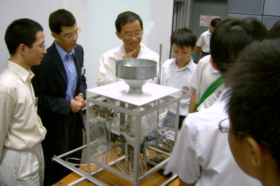Figure 3: Mr. C.Y. Lam (third left), Director of the Hong Kong Observatory, and the judges - Dr. C.L. Yip (leftmost), Department of Computer Science and Dr. Y.S. Hung (second left), Department of Electrical & Electronic Engineering of the University of Hong Kong appreciating the rain gauge of the Senior Champion Team with participating students.