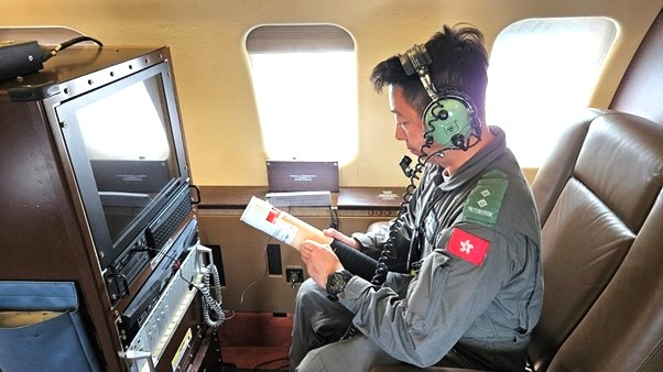 A crew member of the Government Flying Service connecting a dropsonde for inspection and configuration of parameters before the mission.
