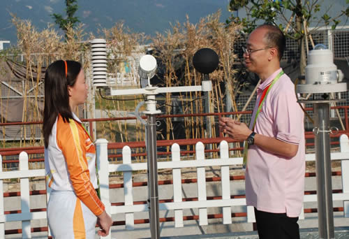 图（二）天文台科学主任李国麟（右方）与广州市气象局业务处副处长熊亚丽（左方）在从化马术比赛场地的天气观测场交流有关暑热压力指数的应用心得。